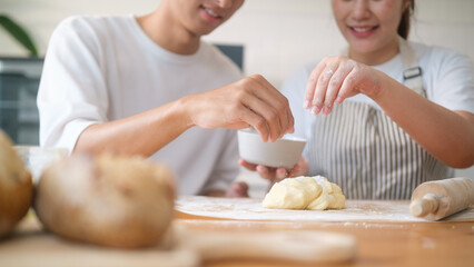 Close up o couple adding flour to cookie dough while baking together in the kitchen.