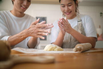 Happy couple clapping flour off their hands while baking cookies together in the kitchen.
