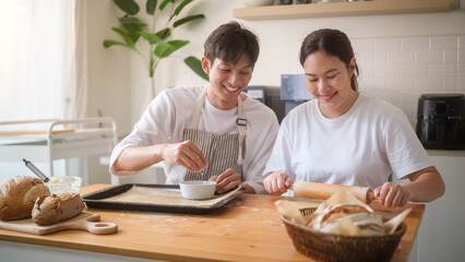 Happy couple enjoying baking at home, flattening dough with a rolling pin.