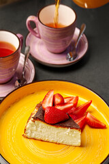 Delicious cheesecake with strawberries and two cups of tea being poured