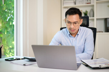 Concerned businessman looking at laptop screen while working at office desk.