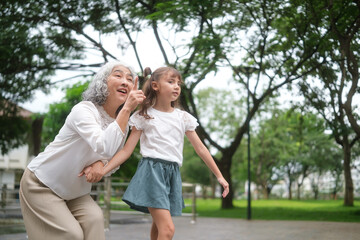 Fototapeta premium Grandmother and little girl spending quality time outdoors, sharing joy and family connection.