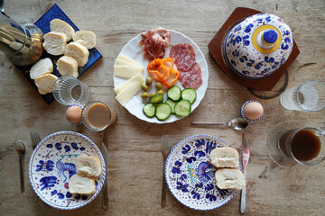 Rustic breakfeast table with Coffee, water and plate with Salami and cheese, olives and more