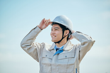 ヘルメットをかぶる作業服姿の男性