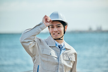 ヘルメットをかぶる作業服姿の男性