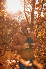 Obraz premium Amateur birdwatcher observing birds and other animals in nature with binoculars.