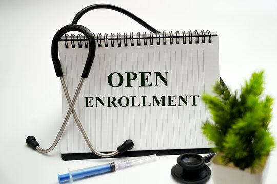 Medical concept. White notepad with the words open enrollment and a stethoscope on a White background.