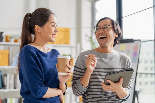 business development teamwork is standing and discussing a new rebranding and strategy. The two business people focus on the future target market and present success, using market research data 
