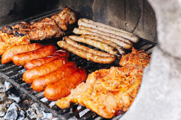 Grilled sausages and meat. Outdoor barbecue with pork and bratwurst. Juicy meat sizzling on charcoal grill. Summer picnic or garden party food. Tasty smoky dish with crispy roasted surface.