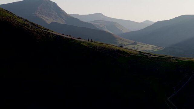 Aerial landscape reveal of people hiking in mountains with morning sunrise