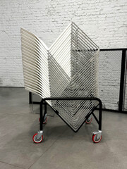 Stacked chairs on a transport cart. Modern public space organization concept. Handheld mobile photo, selective focus, non AI