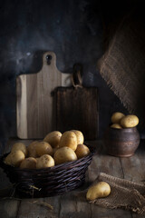 Fresh washed potatoes in a wicker basket on a wooden table