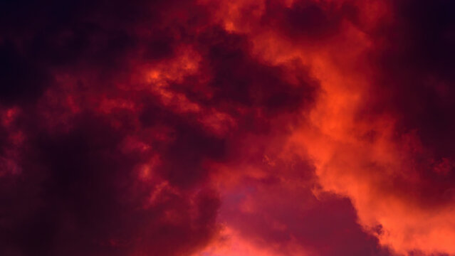 red cloudy mystical sky. artistic photo of clouds illuminated by setting sun. background dramatic sunset cloudscape. horizontal side view in 16x9 format