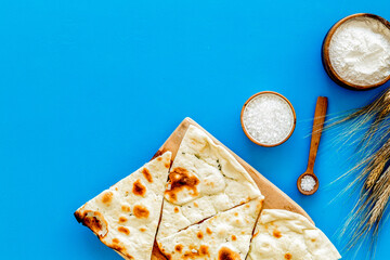 Focaccia ingredients. Wheat ears, flour, oil near bread on blue background top-down copy space