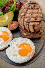 A Delicious Breakfast Plate Featuring Grilled Meat, Sunny-Side-Up Eggs, Fresh Salad, and Hearty Whole Grain Bread for a Nutritious Start to Your Day