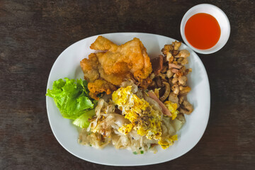 Stir fried rice noodles with roasted and fried chicken served with fresh lettuce and chili sauce. Close up stir fried fresh rice fat noodles with chicken and egg. Asian food style. Delicious Thai food