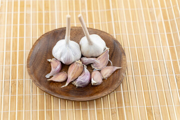 some garlic lies on a craft wooden plate on a neutral background