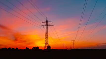 Summer sunset or sundowner view with a dramatic sky and overland high voltage lines near Tabertshausen, Aholming, Deggendorf, Bavaria, Germany