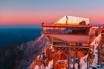 Alpine sunset or sundowner with reflections in a glass building at Mount Zugspitze, Top of Germany,...