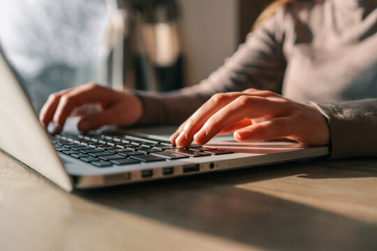 Close-up of hands typing on a laptop keyboard with soft natural light creating a warm and productive work atmosphere - Powered by Adobe