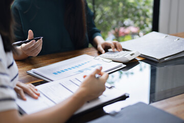 Female office worker sitting on desk managing financial files and reviewing reports