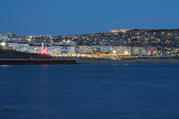 Obraz premium Evening view of Nagaev Bay and the city of Magadan. Magadan Region, Russia. There is a lighthouse and a park on the seashore. Residential buildings in the distance. The coast of the Sea of ​​Okhotsk.