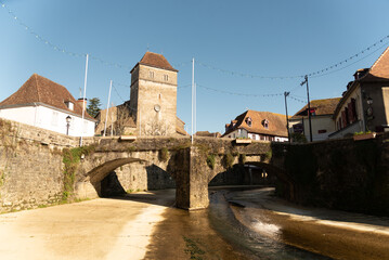View of the impressive medieval architecture of the small stone houses with a beautiful riverside bridge in the touristy southern French village of Sales de Bearn at sunset.