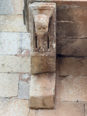 Weathered stone corbel with carved human face at San Juan Bautista Church