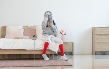 A girl in fencing gear is sitting and rest on the bed