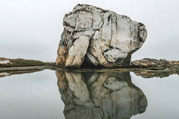 a rock with a reflection in the water