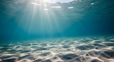 Obraz premium Sunbeams illuminate a serene underwater scene, showcasing a sandy ocean floor and crystal-clear turquoise water.