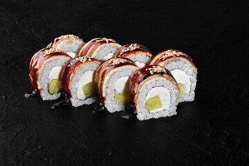 Delicious canada rolls with eel, cream cheese, and cucumber lying on dark background