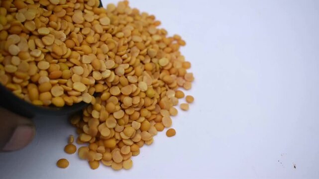 Video of split pigeon peas, or toor dal, being spilled onto a paper from a bowl