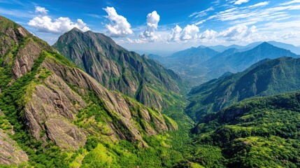 Naklejka premium Lush green mountains and deep valleys under a bright blue sky with scattered clouds