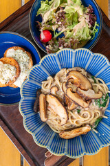 top view mushroom pasta served with cheese-stuffed chicken breast and fresh garden salad at vertical composition