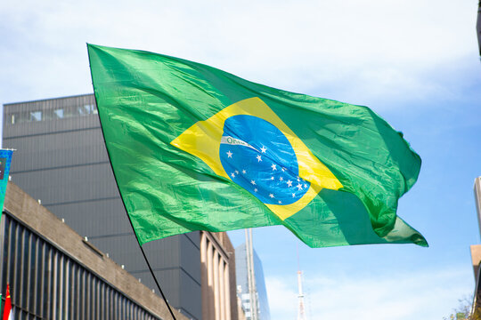Brazilian flag waving on Paulista Avenue on protest day. - Powered by Adobe