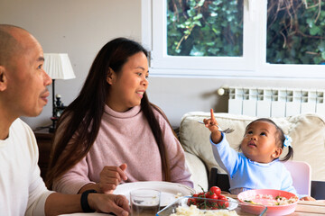 Happy family enjoying healthy meal together with baby girl looking up