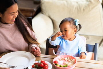 Baby girl eating healthy food with spoon