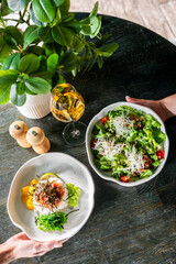 Top view of a wooden table with a healthy meal setting, including salad, rice with vegetables, a glass of wine, and salt and pepper shakers
