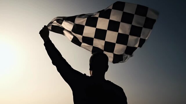 Dynamic silhouette shot of a person waving a checkered flag against a dramatic gradient sky Represents racing victory championship triumph finish line success a