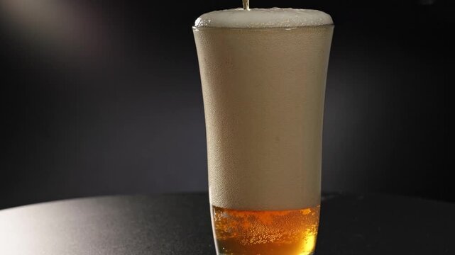 Super slow motion close-up of beer, alcohol, and carbonated drink beverage and ale brew pouring and spilling into a glass and over pouring out of container, with bubbles and carbonation in a studio 4k