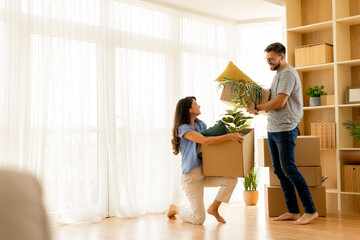 Couple joyfully moving into their new home with plants and boxes