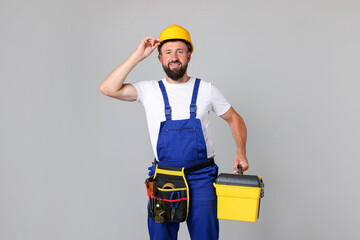 Professional repairman with tool box on grey background