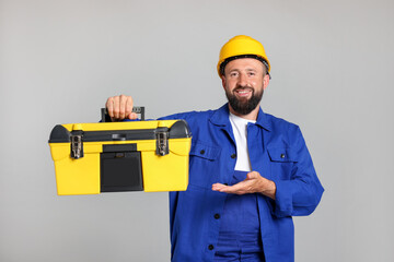 Professional repairman with tool box on grey background