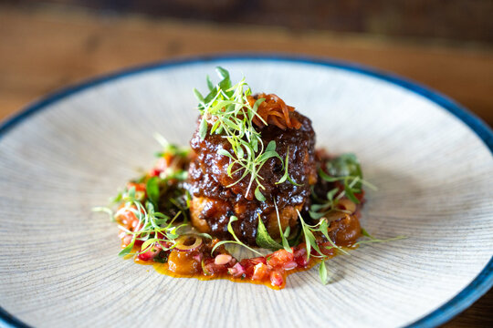 Gourmet Gericht mit geschmortem Fleisch, garniert mit frischen Microgreens und Tomaten Salsa