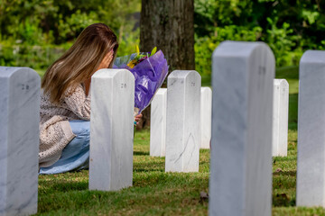 Kneeling in Sorrow: A Bride's Silent Tribute at a Military Cemetery