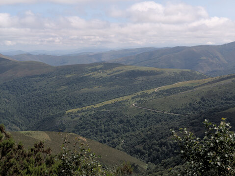 Winding mountain road through Camargo Valleys lush landscape - Escape to serene Cantabria, Spain, where lush valleys meet majestic mountains & panoramic views await.