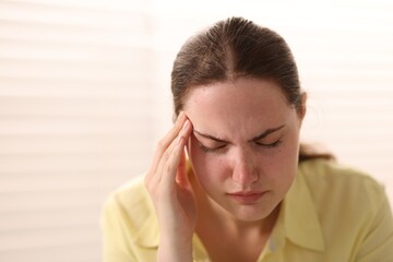 Fototapeta premium Young woman suffering from headache at home, space for text