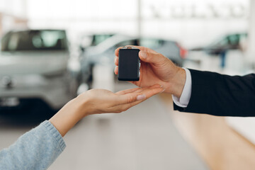Car salesman giving car keys to a client in a dealership