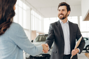 Car salesman shaking hands with client in dealership